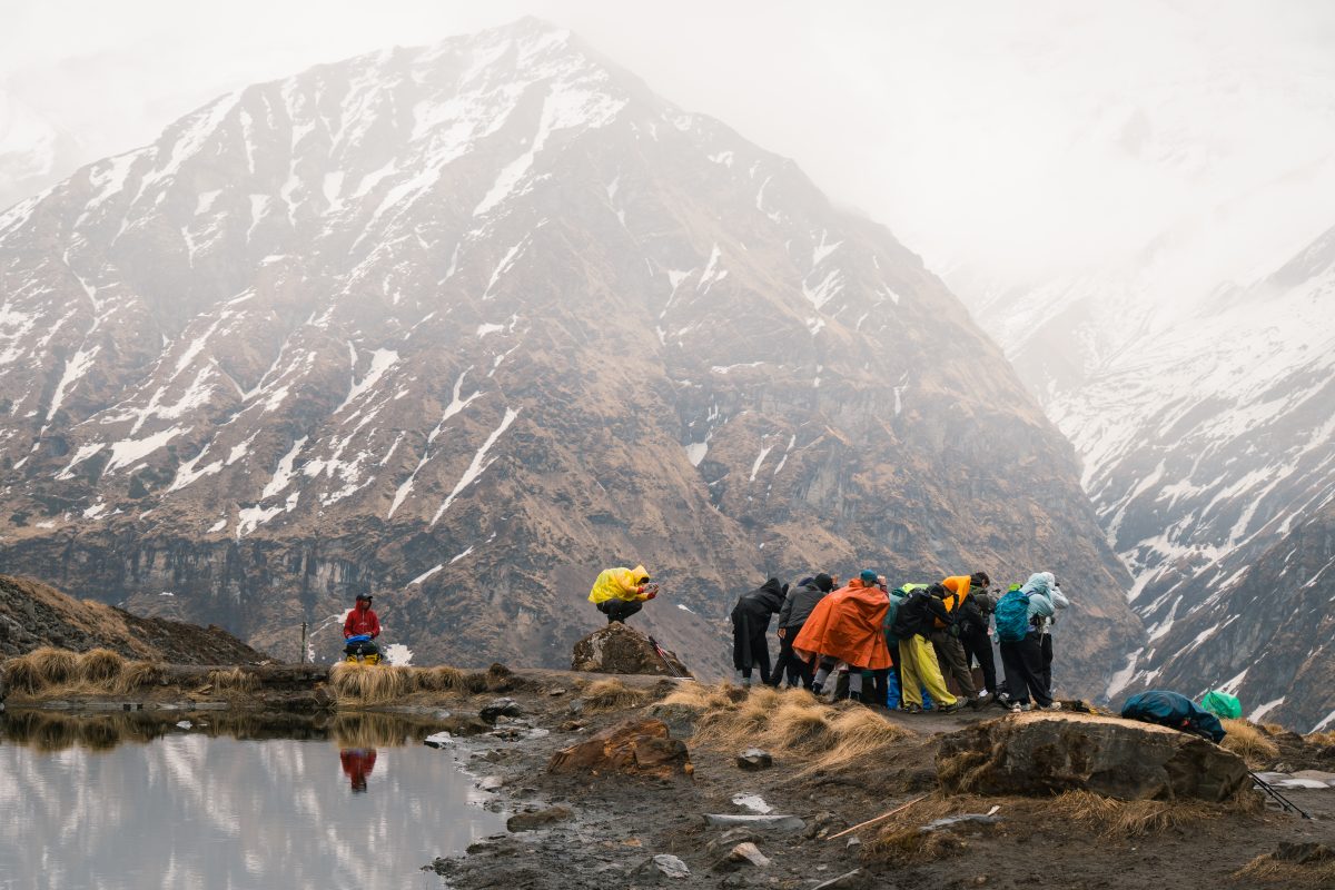 Solo female trekker walking on a mountain trail with snow-capped Himalayas in the background, trekking in Nepal.